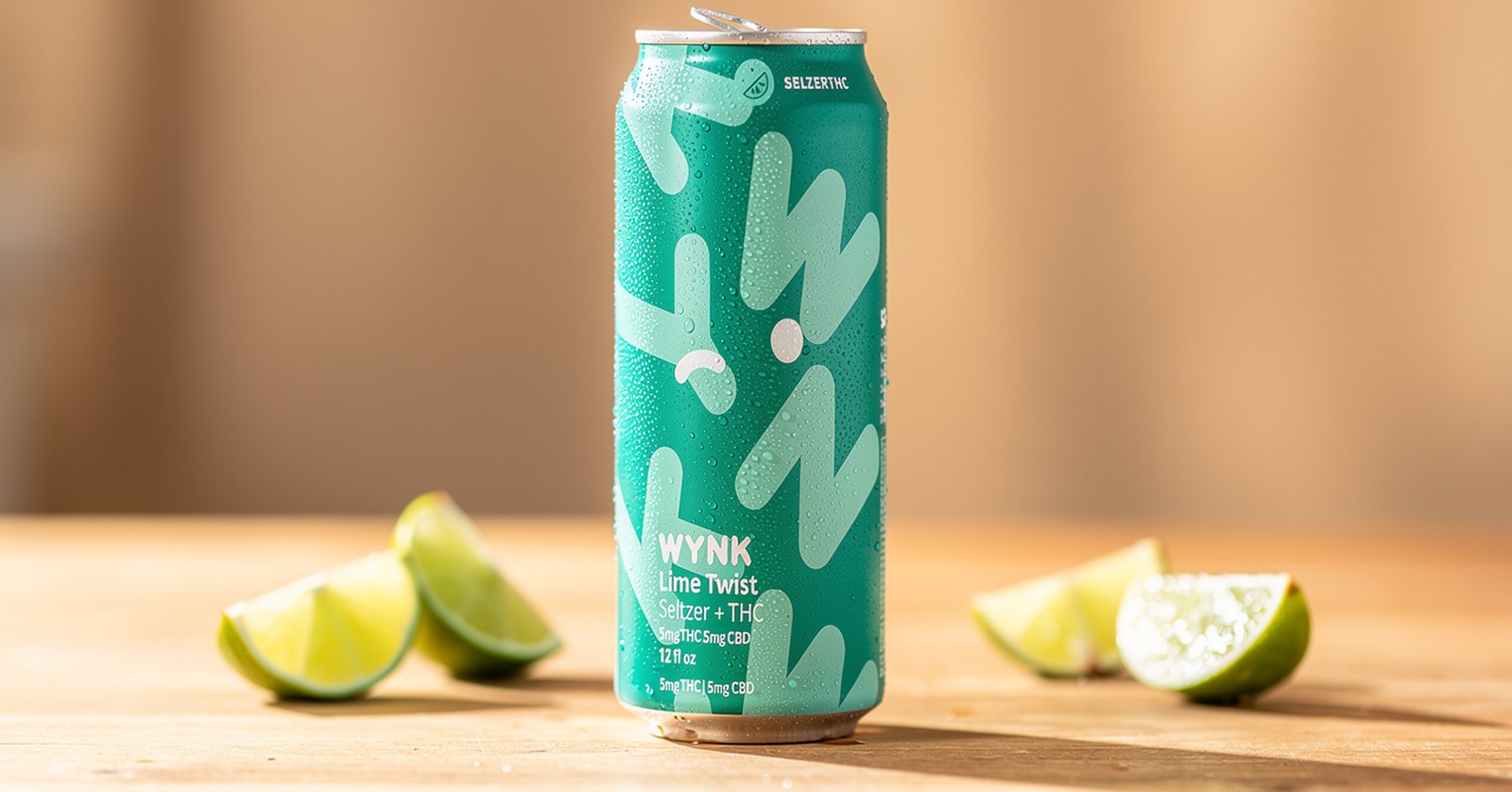 Wynk Lime Twist THC seltzer can on a wooden table with lime wedges